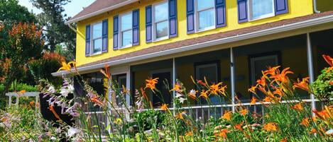 A yellow house with a porch and multiple windows.