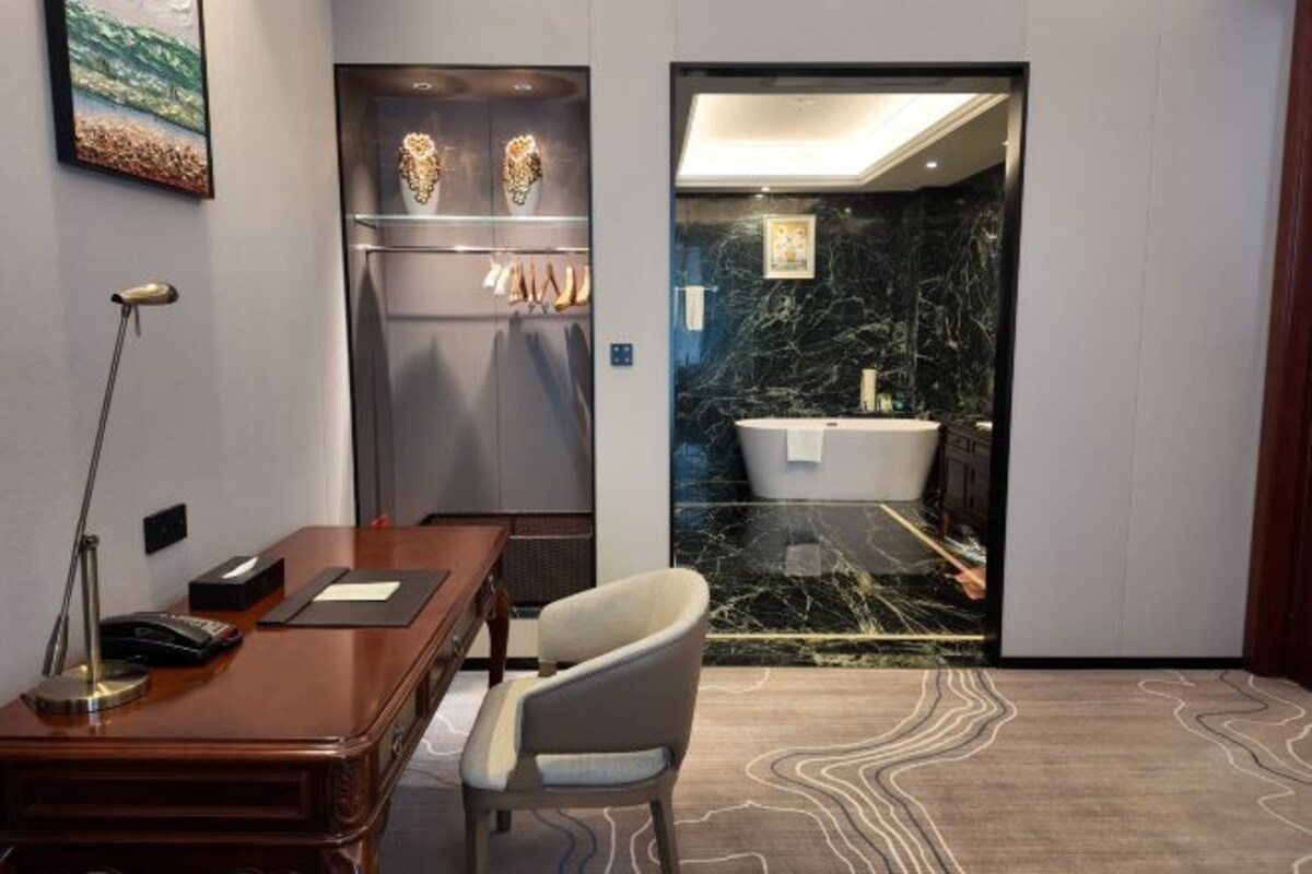 A hotel room with a desk, chair, and a bathroom visible through an open door.