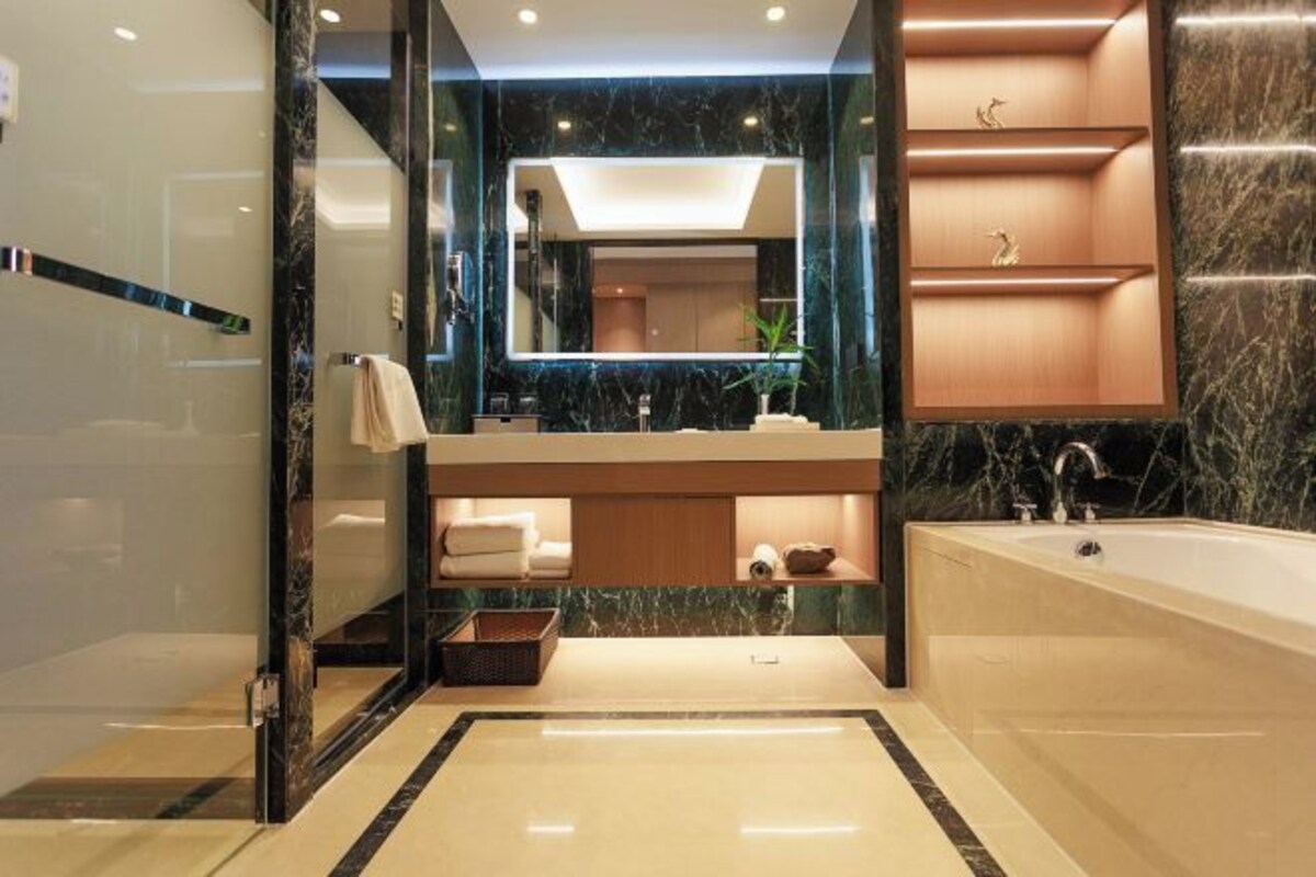A modern bathroom with a large mirror, a bathtub, and a vanity with a sink.
