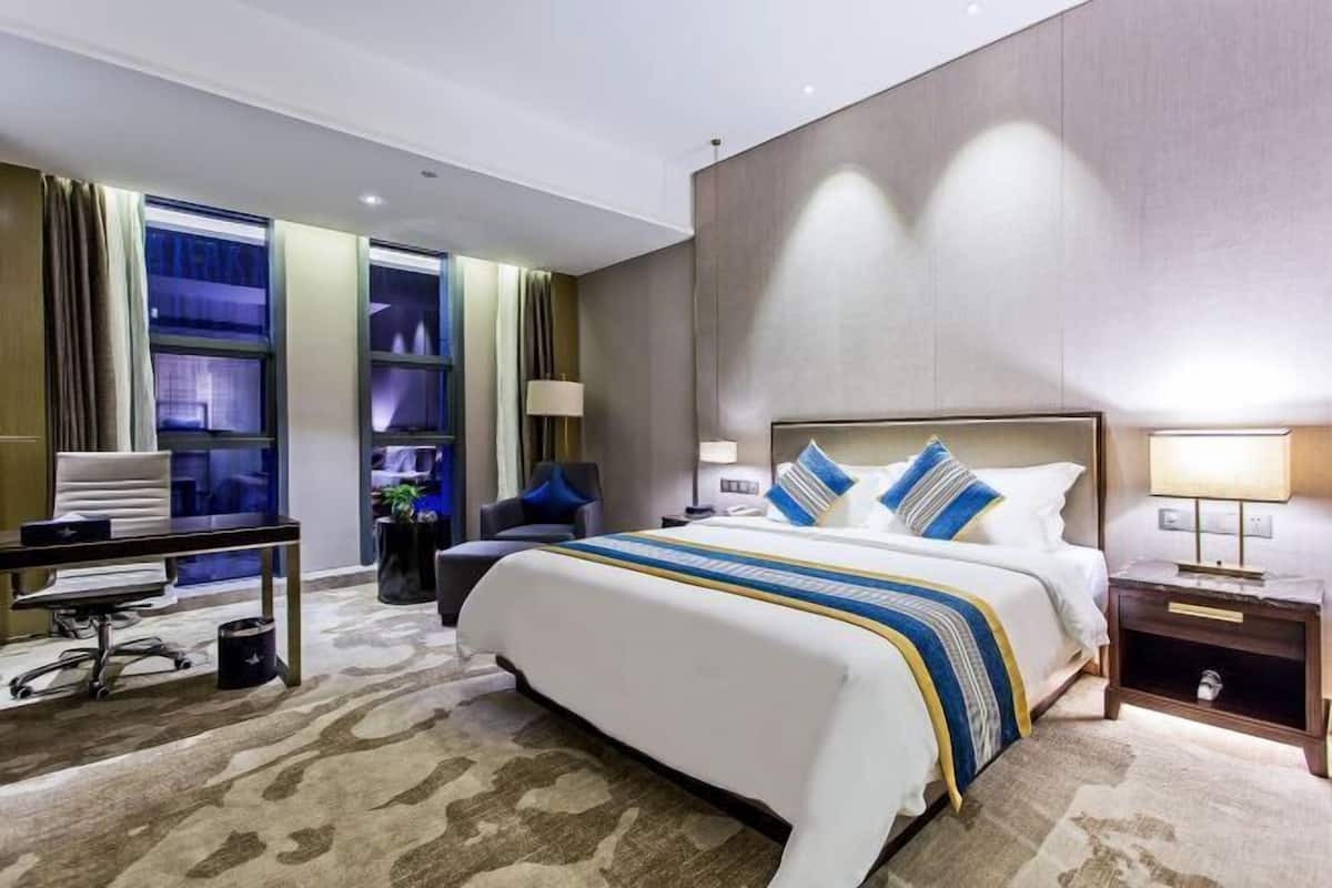 A modern hotel room with a large bed, a desk, and a chair.