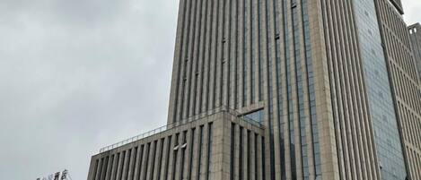 A tall building with vertical lines and a glass facade.