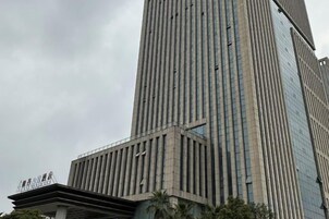 A tall building with vertical lines and a glass facade.