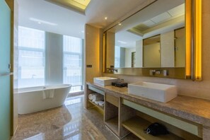 Un baño moderno con una bañera independiente, dos lavamanos, un espejo grande y un mueble de tocador con estantes.