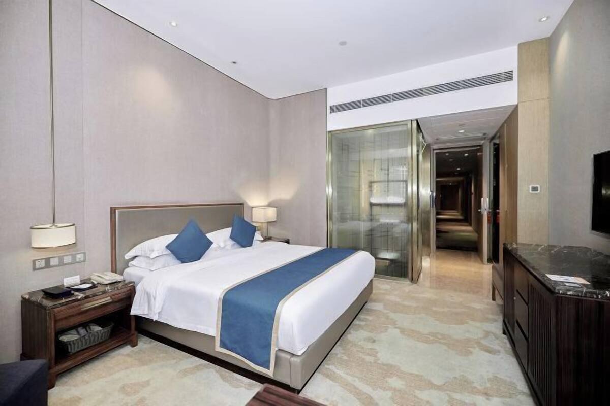 A hotel room with a large bed, bedside tables, a desk, and a TV.