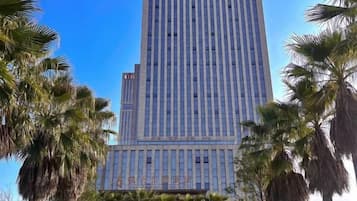 A tall building with a modern design, surrounded by palm trees.