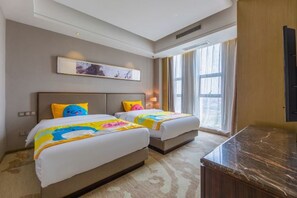 Habitación de hotel con dos camas, un ventanal grande, una encimera de mármol y televisor montado en la pared.