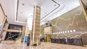 A modern hotel lobby with a reception desk, a staircase, and a large pillar. - Fontaine Hotel (Yingtan)
