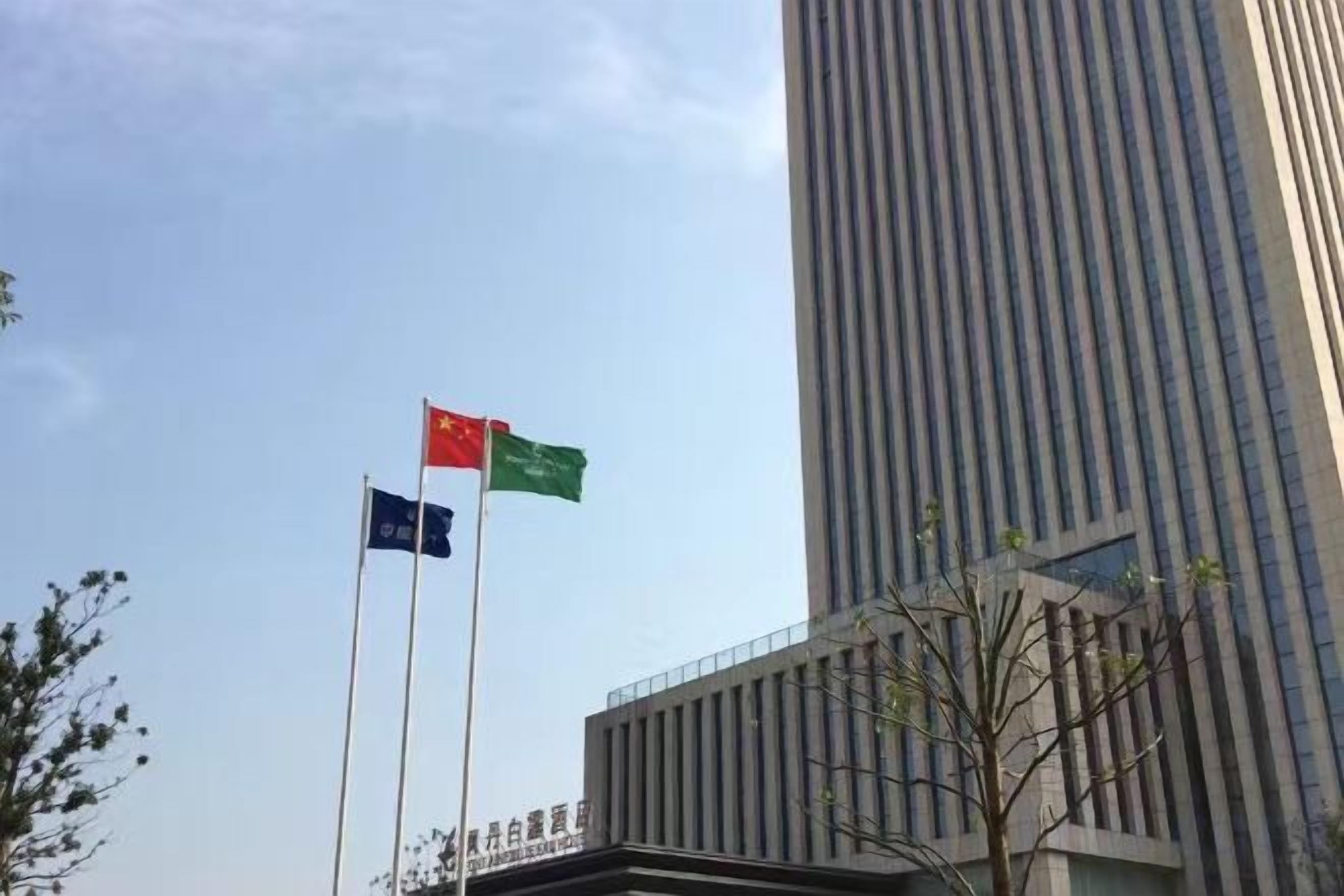 A tall building with three flags on flagpoles.