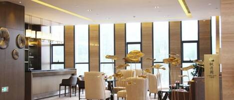 A hotel lobby with a reception desk, seating area, and large windows.