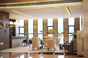 A hotel lobby with a reception desk, seating area, and large windows. - Fontaine Hotel (Yingtan)