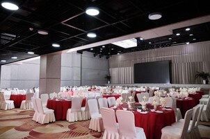 Un salón de conferencias con mesas redondas, sillas y una pantalla grande.