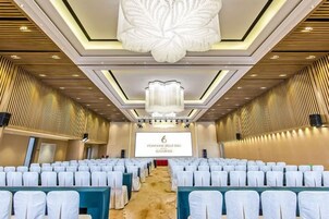 A conference room with rows of chairs, a large screen, and a chandelier.