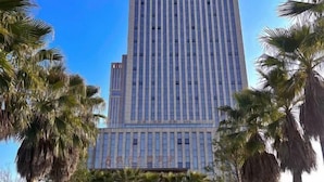 A tall, modern building with a grid of windows and a clear blue sky in the background. - Fontaine Hotel (Yingtan)
