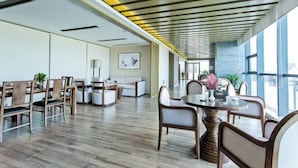 A modern hotel lobby with a long reception desk, comfortable seating, and large windows offering views. - Fontaine Hotel (Yingtan)