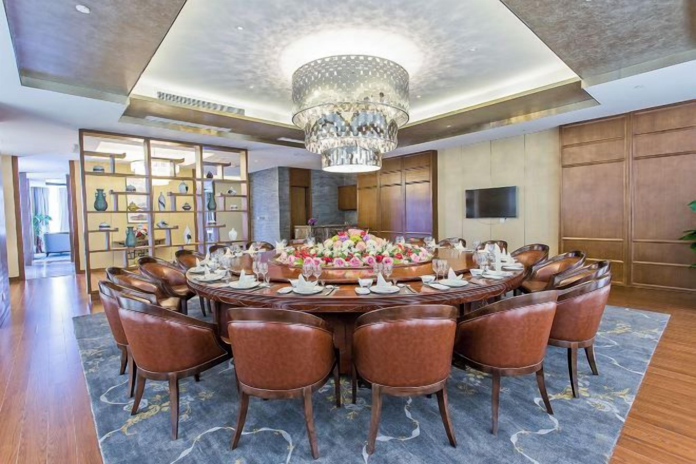 A formal dining room with a round table, multiple chairs, and a chandelier.