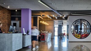 Eine moderne Lobby mit einer Rezeption, einer großen Uhr und einem Barbereich.
