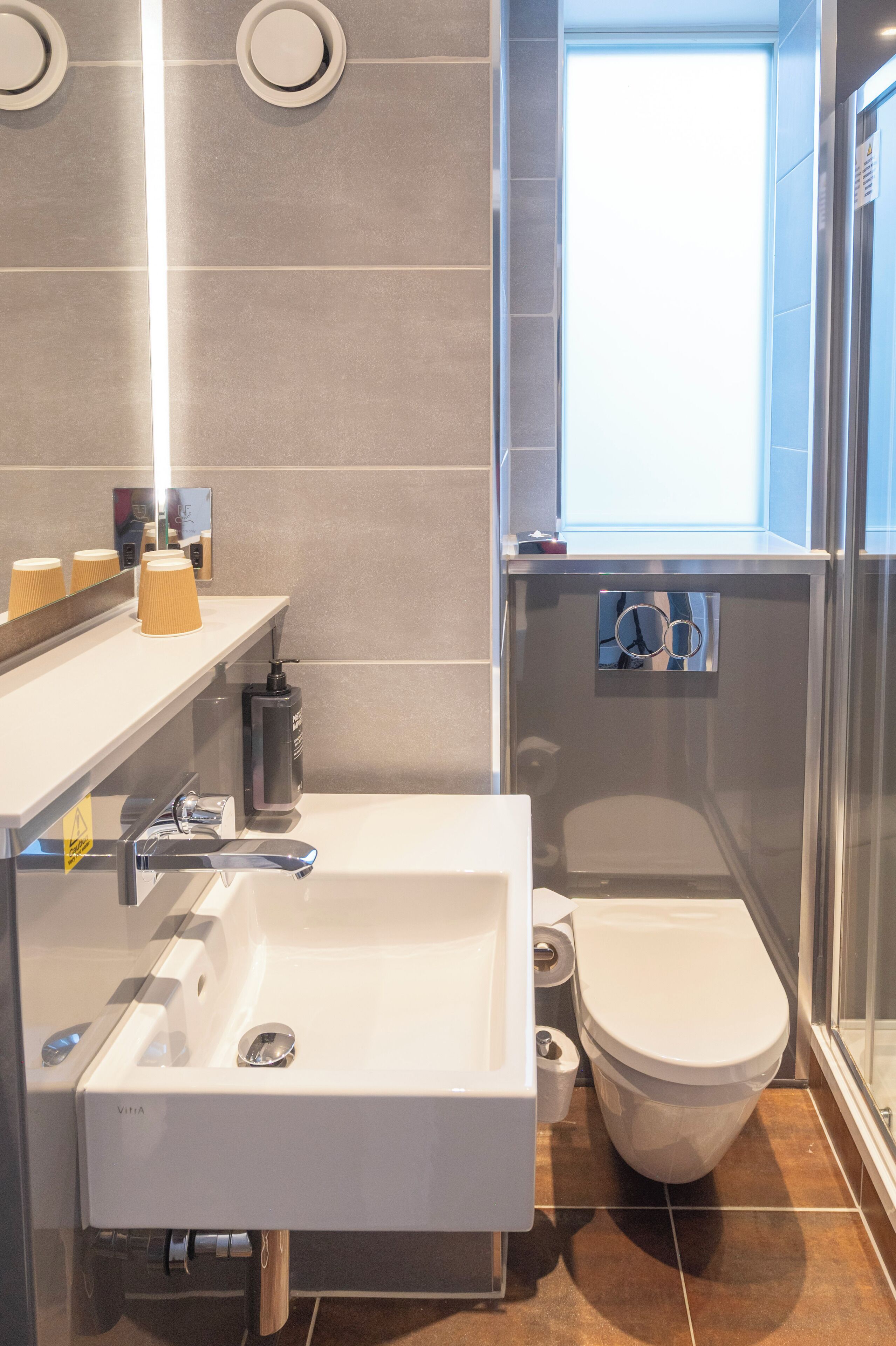 A modern bathroom with a white sink, a toilet, and a shower area.