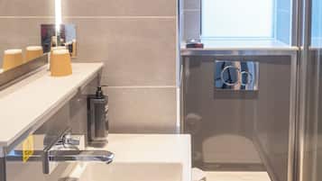 A modern bathroom with a white sink, a toilet, and a shower area.