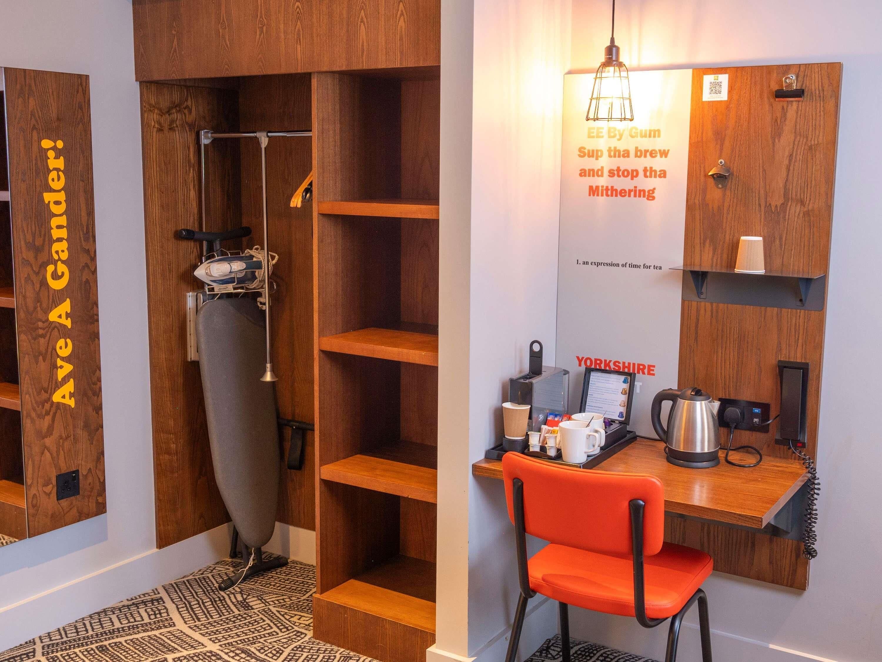 A compact kitchenette with a coffee machine, kettle, and a small shelf.
