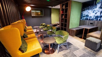 Ein moderner Lounge-Bereich mit einem gelben Sofa, grünen Sesseln und einem kleinen runden Tisch.