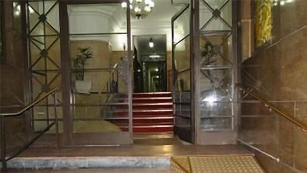 A staircase with metal railings and a tactile paving strip at the bottom.