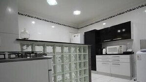 A modern kitchen with white cabinets, a glass partition, and a microwave.