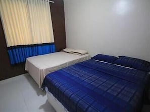 A bedroom with two beds, one with a white bedspread and the other with a blue bedspread.
