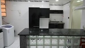 A modern kitchen with black and white cabinets, a black countertop, and a built-in stove.