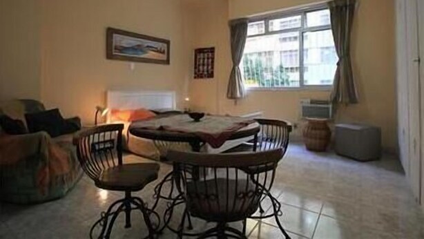 A living room with a round table, two chairs, a sofa, a ceiling fan, and a window with curtains. - GoHouse Julio 201 (Rio de Janeiro)