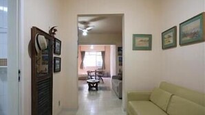 A hallway with a sofa, a dining area in the background, and framed pictures on the wall. - GoHouse Julio 201 (Rio de Janeiro)