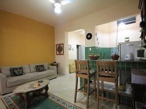 Ein kompakter Wohnbereich mit Sofa, Esstisch, Stühlen und einer Küchenzeile.