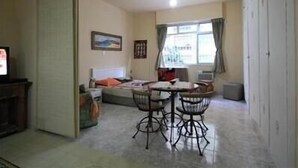 A compact living space with a dining area, a bed, and a television. - GoHouse Julio 201 (Rio de Janeiro)