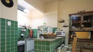 A kitchen with green tiles, a stove, a microwave, and a wooden cabinet. - GoHouse Julio 201 (Rio de Janeiro)
