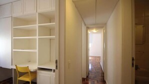 Ein Flur mit einem weißen Kleiderschrank, einem gelben Sessel und einem gemusterten Boden.