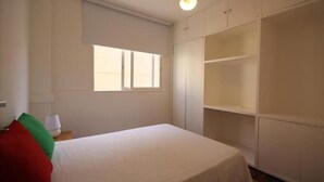 Ein Schlafzimmer mit Bett, Fenster und Einbauschränken.