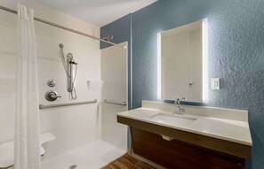 A bathroom with a shower, toilet, and sink with a large mirror.