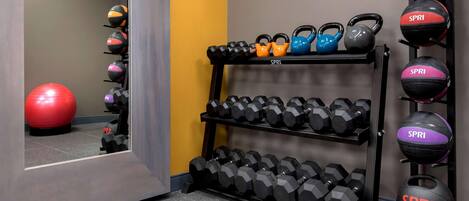 Une salle de sport équipée de kettlebells, d’haltères et de ballons d’exercice.