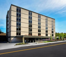 A modern hotel building with a flat facade, large windows, and a clear sky.