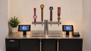A tap system with four different beer taps, two digital displays, and a potted plant. - The Hayes Street Hotel, Trademark Collection by Wyndham (Nashville)