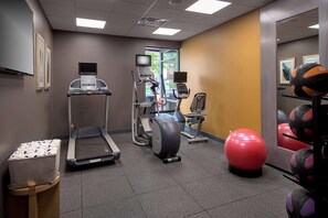 A fitness center with treadmills, an elliptical, a stationary bike, and exercise balls.