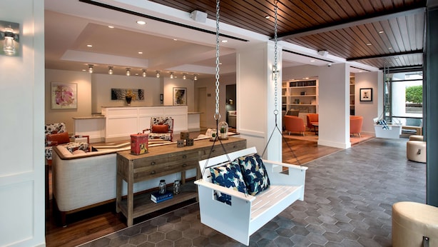 Un salón amplio con un sofá blanco, un columpio colgante y una mesa de centro de madera.