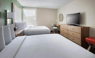 Habitación de hotel con dos camas, un escritorio, un televisor y una silla.