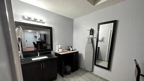 A modern bathroom with a dark vanity, a sink, a mirror, a towel rack, and a shower area.