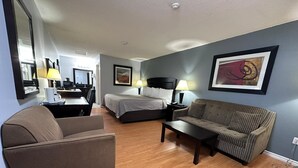 A hotel room with a bed, a sofa, a chair, a desk, and a lamp.