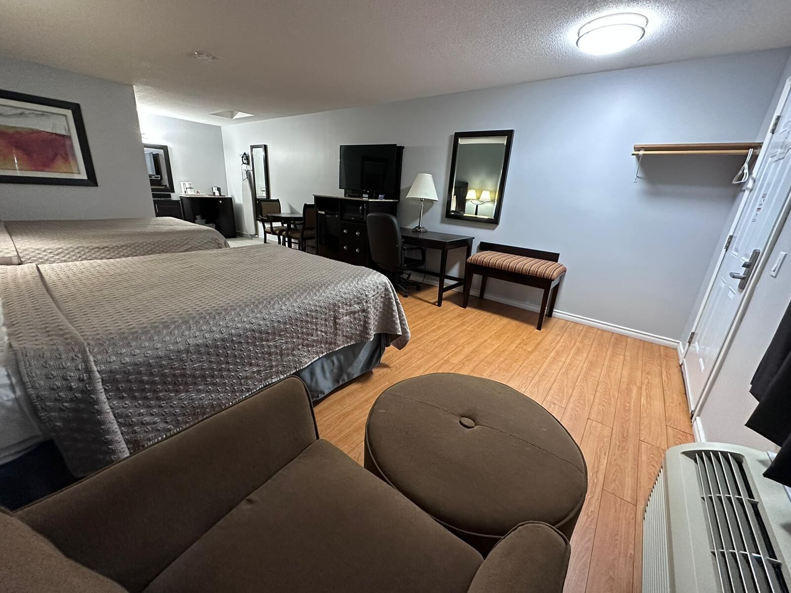 Una habitación de hotel con una cama grande, un escritorio, una silla, un banco, un televisor y un armario.