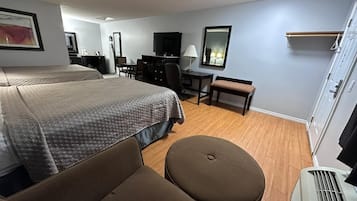 Una habitación de hotel con una cama grande, un escritorio, una silla, un banco, un televisor y un armario.