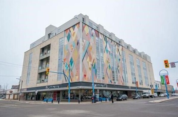 A multi-story building with a large, colorful mural on its facade. - Downtown Loft Style Condo Heated Parking (Saskatoon)