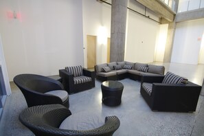 A modern lounge area with a sectional sofa, two armchairs, and a round coffee table. - Downtown Loft Style Condo Heated Parking (Saskatoon)
