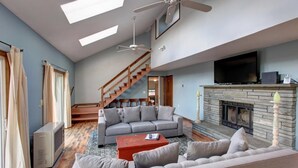 A spacious living room with a grey sofa, a red coffee table, and a fireplace.
