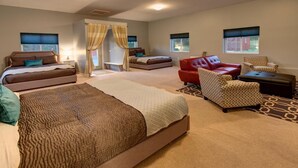 A spacious bedroom with two large beds, a red sofa, patterned armchairs, and a small table.